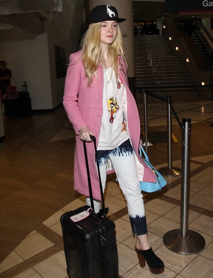 Elle Fanning wears dip-dyed jeans with a pastel pink coat, scorpion-printed hat and heeled clogs