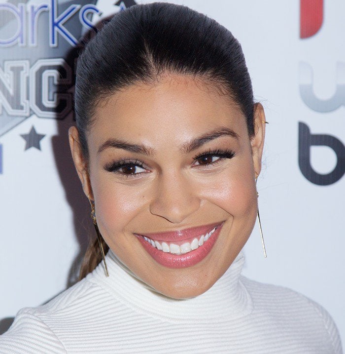 Jordin Sparks radiates elegance in a sleek, high-neck white dress paired with simple yet striking earrings at the Red, White, and Black Super Bowl Party