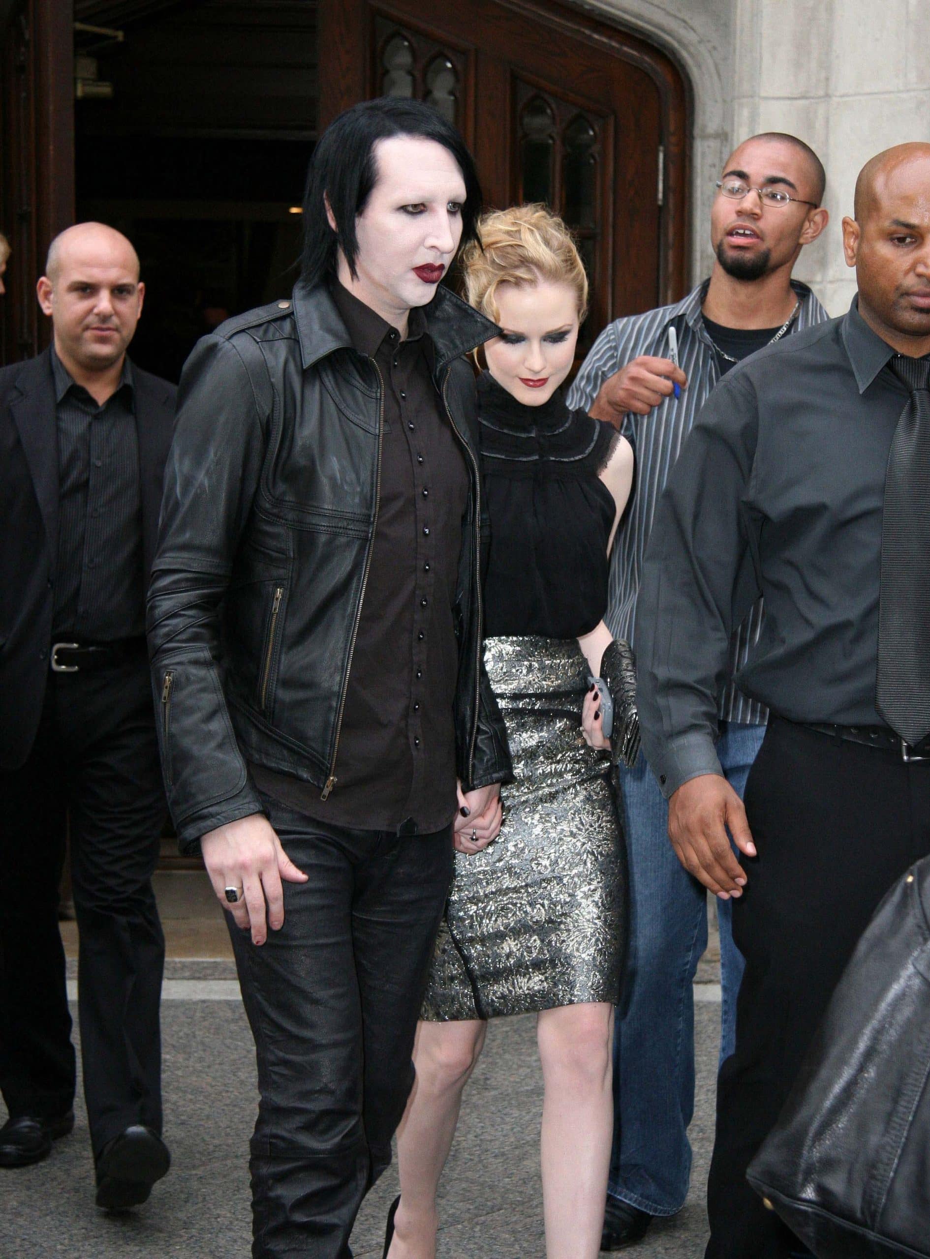 Marilyn Manson and Evan Rachel Wood step out in coordinating edgy-glam looks, with Evan turning heads in a metallic brocade pencil skirt, black sleeveless blouse, and classic black stilettos, while Manson sticks to his signature style in head-to-toe black leather
