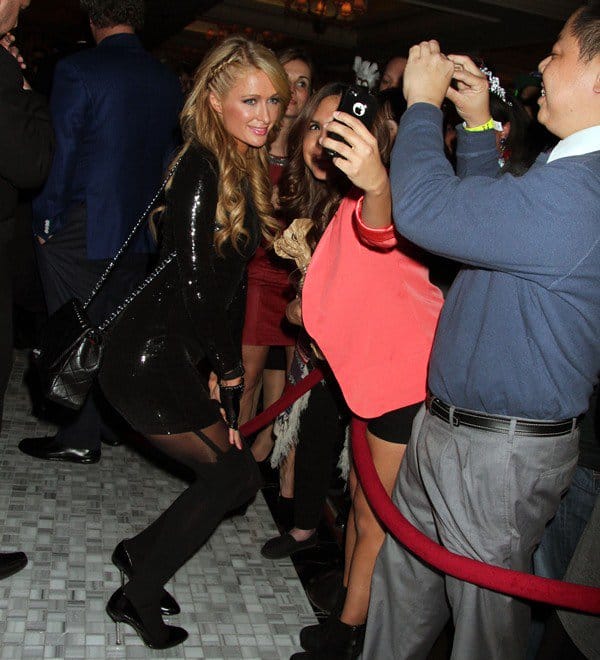 Paris Hilton poses with fans, showing off her voluminous waves and sleek makeup while wearing a sequined mini dress at Hyde Bellagio, Las Vegas, December 31, 2013