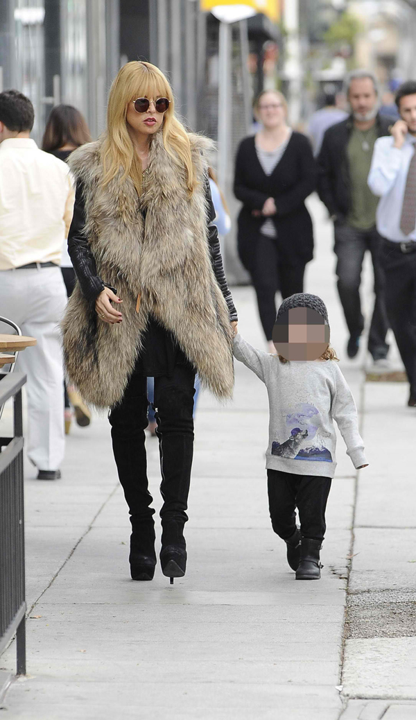 Rachel Zoe wears an oversized fur vest over a leather jacket while walking with her son in Los Angeles