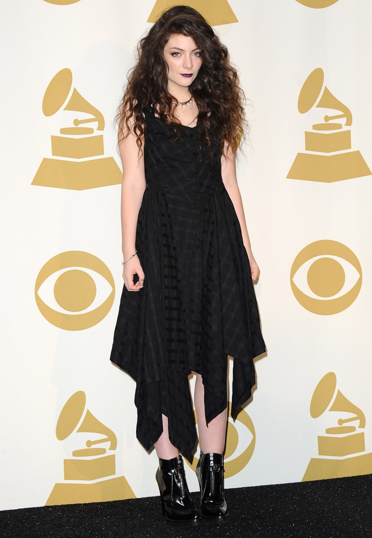 Recording artist Lorde poses in a black dress with matching boots in the press room during The GRAMMY Nominations Concert Live!! Countdown To Music's Biggest Night