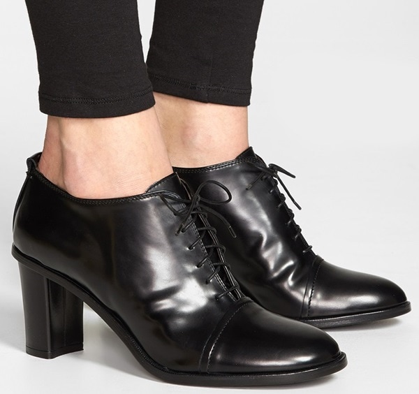 A smooth, lustrous finish illuminates the pristine profile of an essential leather-crafted ankle bootie