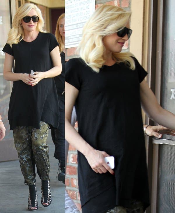 L.A.M.B. founder and designer Gwen Stefani wearing a black maternity dress over a pair of loose olive green pants and a strappy pair of high-heeled sandals