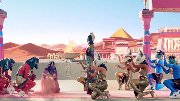 Katy Perry reigns as 'Katy-Patra,' surrounded by minions in metallic gladiator sandals and Diadora sneakers