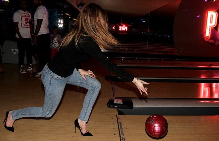 Khloe Kardashian bowls in a black sweater, tight jeans and stiletto heels