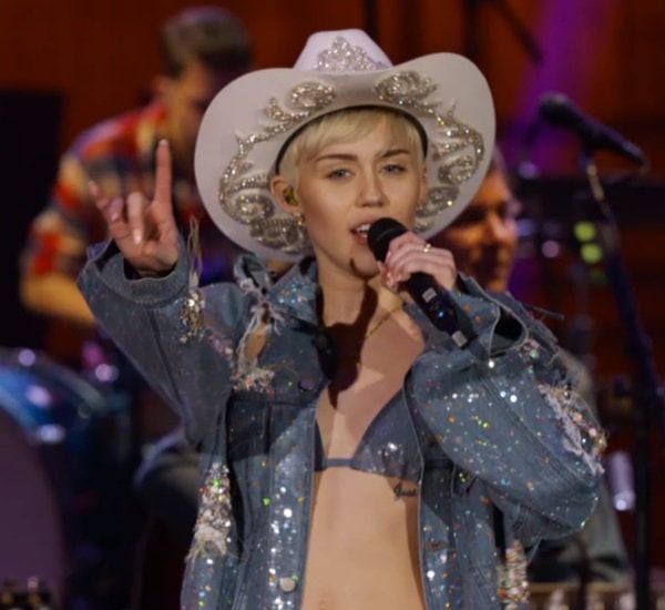 Miley Cyrus wearing a distressed denim jacket with a bikini top