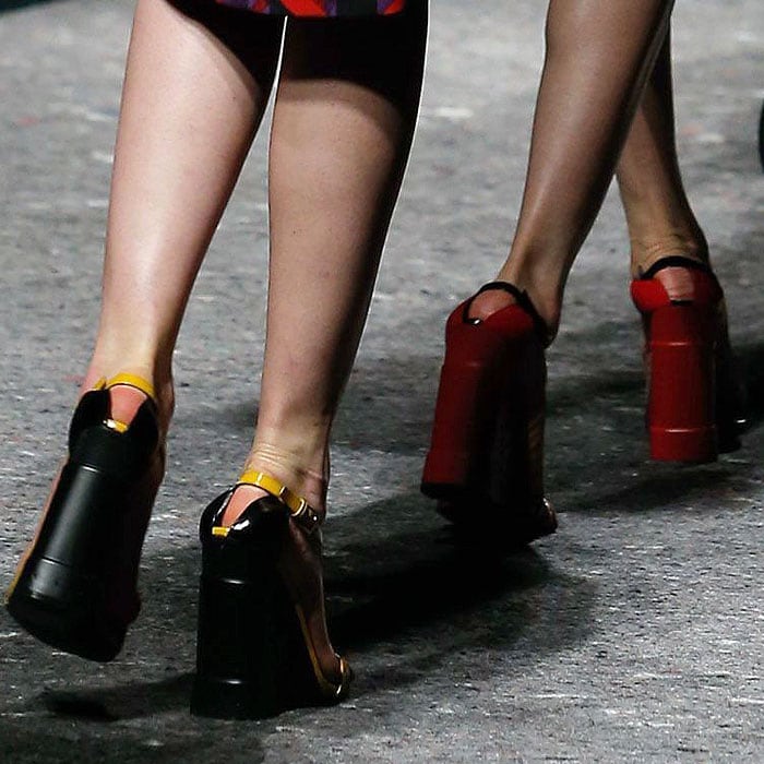 Prada's dramatic wedge heels in bold black and red hues, paired with contrasting yellow accents, exude a powerful statement