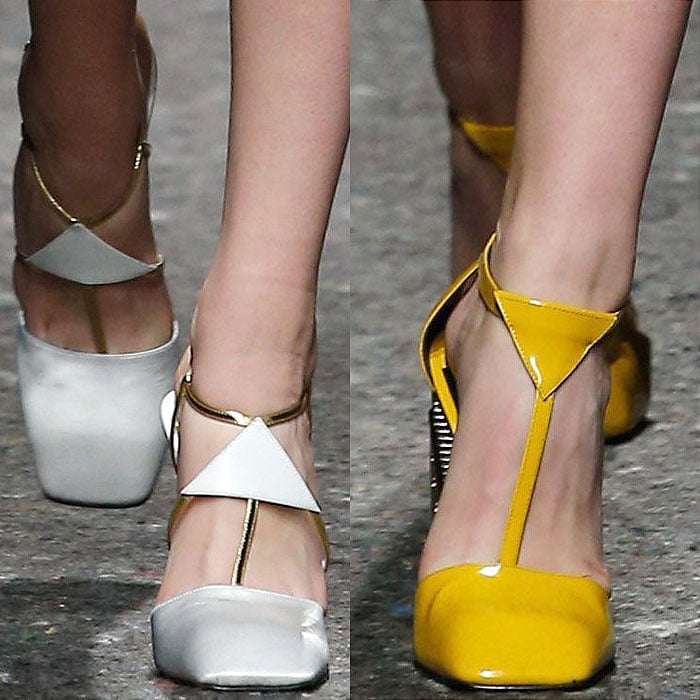 Prada's striking pumps from the Fall 2014 collection feature bold T-strap designs with triangular accents, showcased in high-gloss white and vibrant yellow, blending modern geometry with playful color statements