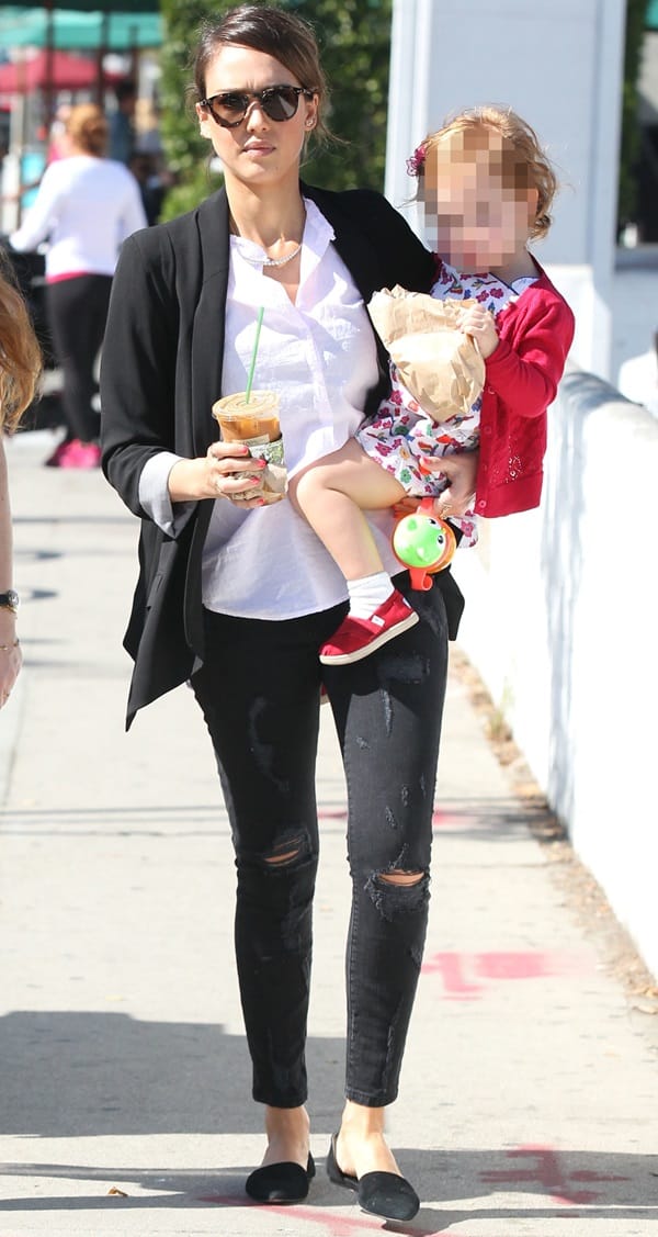 Jessica Alba perfects street style with her sleek updo, oversized sunglasses, and effortlessly chic ensemble featuring a black blazer, ripped skinny jeans, and minimalist flats