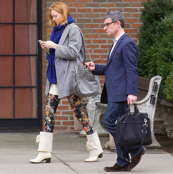 Lily Cole pairs a vibrant blue scarf with a coat, floral leggings, and white boots