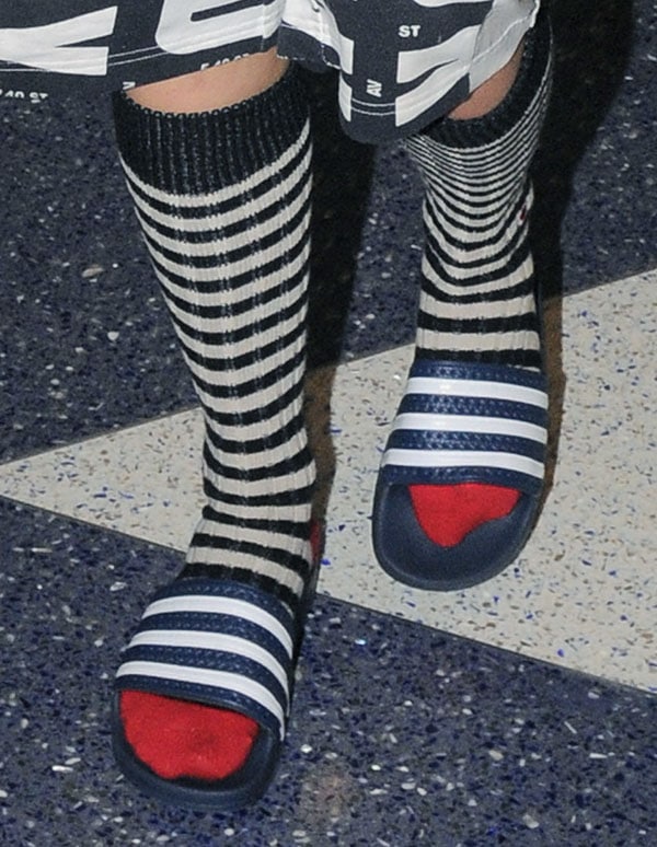 Rita Ora wearing striped red-toed socks and rubber pool-slide sandals