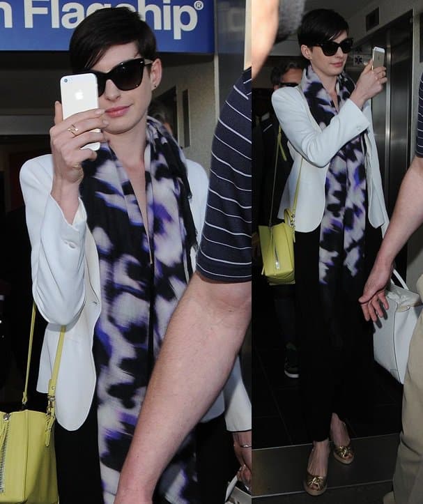 Anne Hathaway playfully uses her phone to fend off paparazzi at LAX after her flight from Florida on March 10, 2014