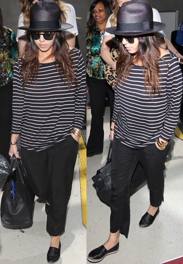 Kourtney Kardashian in a long-sleeved striped shirt, black pants