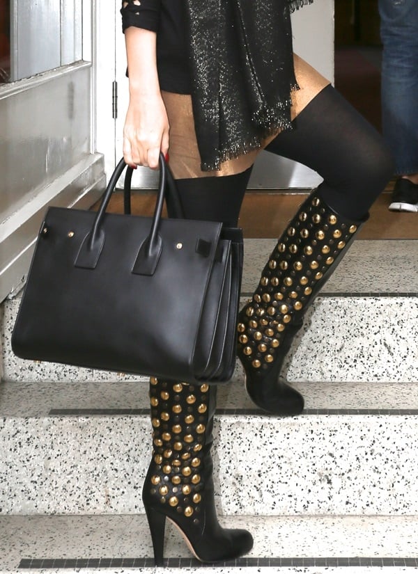 Kylie Minogue pairs her chic black handbag with eye-catching knee-high boots adorned with gold buttons