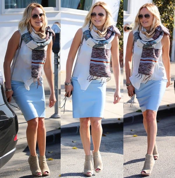 Malin Akerman effortlessly blends casual and chic in a breezy white top, pastel blue pencil skirt, and a cozy patterned scarf, completing the look with taupe peep-toe booties and aviator sunglasses