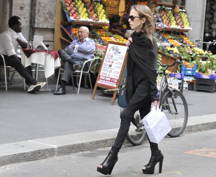 Allegra Versace carries a white Versace shopping bag through the streets of Italy