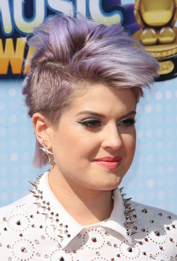 Kelly Osbourne rocks a bold mohawk and studded blouse with edgy makeup and accessories