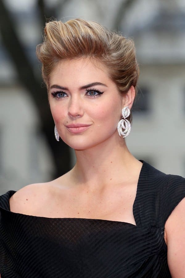 Kate Upton elevated her vintage-inspired look with a voluminous retro updo and sparkling Adler diamond earrings, perfectly complementing her off-shoulder black dress and glamorous red carpet style