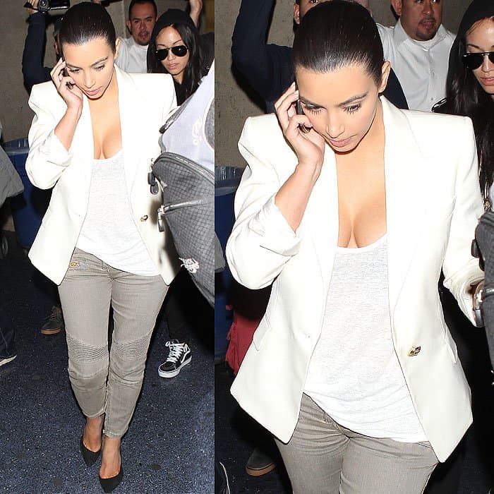 Kim Kardashian, with flawless hair and makeup, arrives at LAX on the phone, looking chic in a Balmain blazer, t-shirt, and gray jeans after a weekend with Olivier Rousteing
