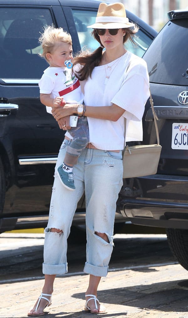 Alessandra Ambrosio elegantly wears oversized pinstriped jeans with contrast stitching, creating a vintage appeal while maintaining a relaxed and stylish look, perfect for a day out with her son