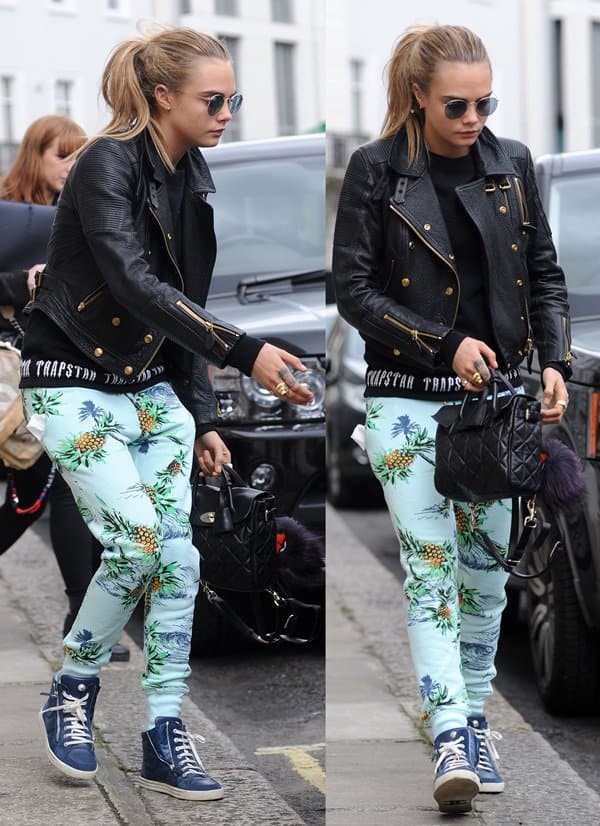 Cara Delevingne showcases a stylish ensemble with Zoe Karssen tropical print sweatpants, a Burberry biker jacket, a Mulberry bag, and Chanel high-top sneakers while out in London