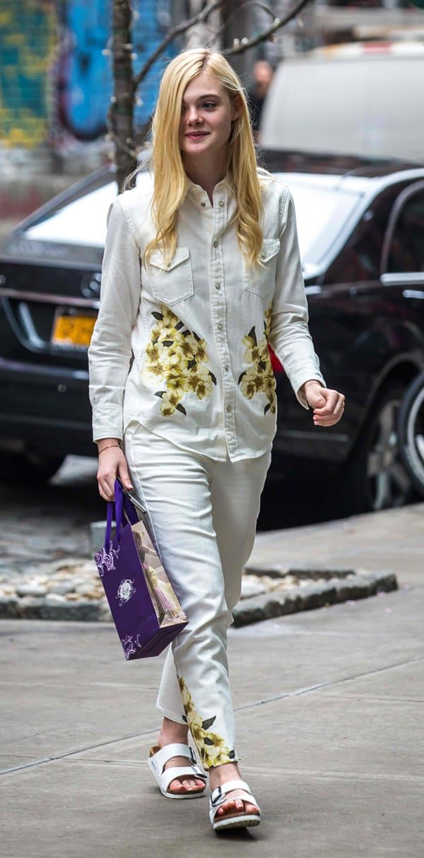 Elle Fanning exudes effortless style in a coordinated floral ensemble, featuring a long-sleeved button-down shirt paired with sleek tapered pants during her outing in New York