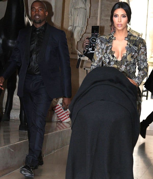 Kanye West, Kim Kardashian, and baby daughter North in a stroller leaving their Parisian residence