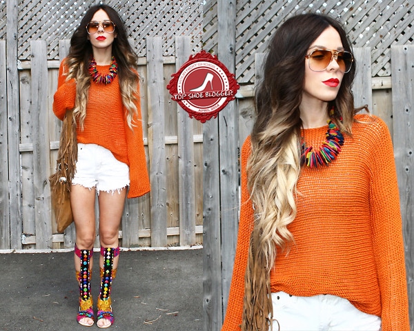 Katie flaunts her legs in an orange knit top and white frayed shorts