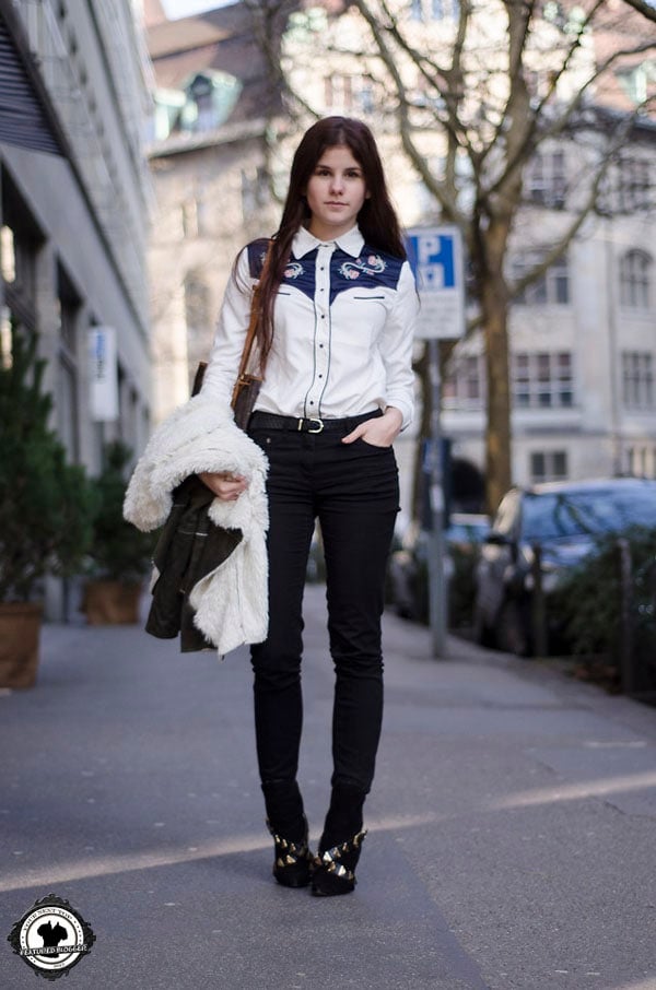Michèle in an embroidered shirt with a statement belt and ripped jeans