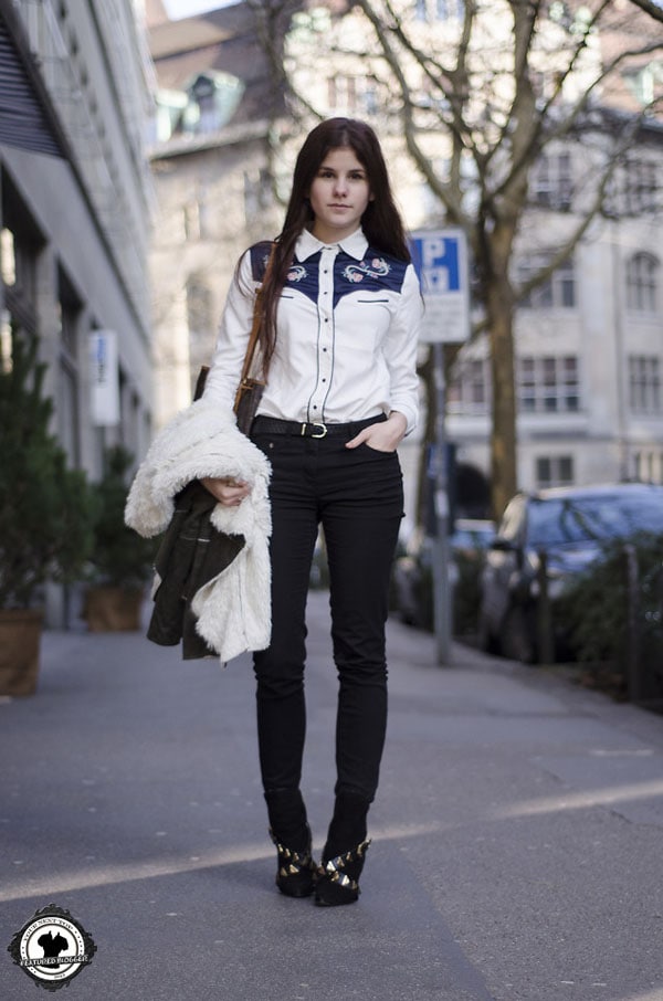 Michèle in an embroidered shirt with a statement belt and ripped jeans