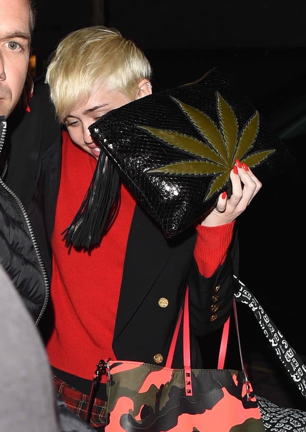 Miley Cyrus carrying a marijuana leaf-embellished snakeskin clutch by Jacquie Aiche