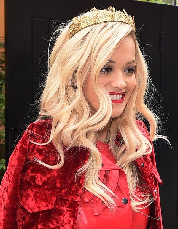 Rita Ora looked cheery in her sexy red leather dress that she topped off with a velvet red jacket and a gold crown