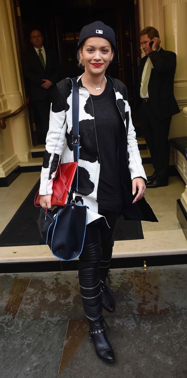Rita Ora leaves her London hotel in a Givenchy cow print coat, black leather Balmain pants, and a Versace Palazzo tote as she heads to rehearsals for her G-A-Y performance on May 10, 2014