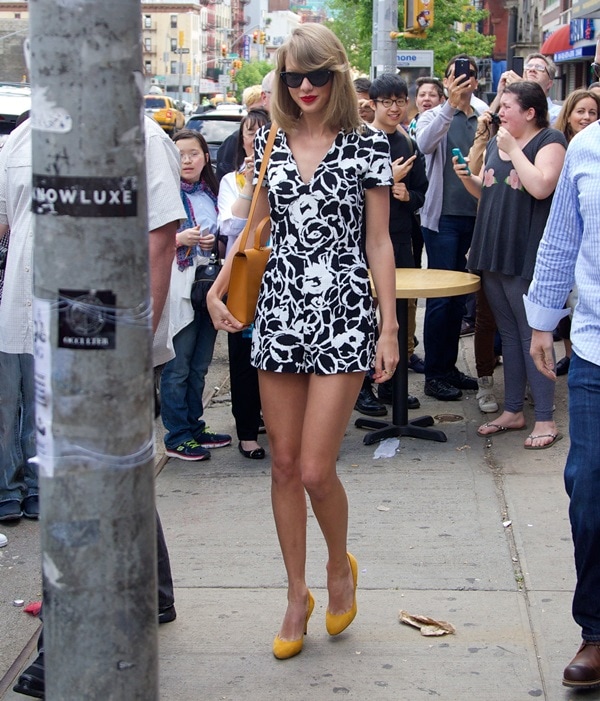 Taylor Swift elevated her city-chic romper with bold accessories: a structured mustard-yellow satchel and matching Gucci suede pumps—easy to replicate with a floral romper, color-pop heels, and a sleek shoulder bag in a complementary hue