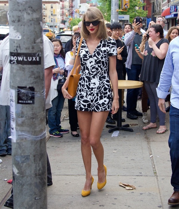 Taylor Swift accessorized with jewelry by Red C Jewels and a streamlined satchel by Bhailiu