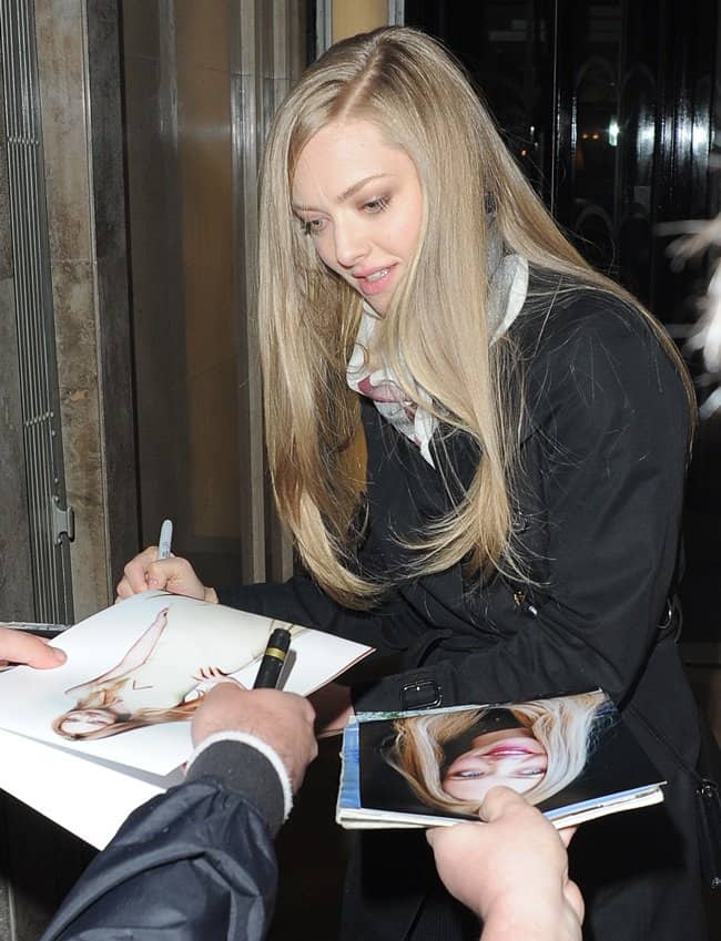 Amanda Seyfried, with her long, sleek hair and natural makeup, signs autographs for fans outside her hotel in London
