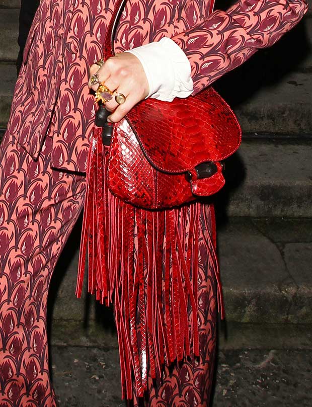 Florence Welch carrying a striking red Gucci fringed python bag, perfectly complementing her Mother of Pearl printed suit at The Other Ball charity event