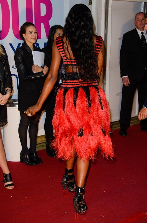 Naomi Campbell's dress features a bold striped design with fringe feathers on its crop top and a fully feathered skirt
