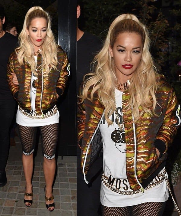 Rita Ora showcases her bold fashion sense in a Moschino tee and fishnet stockings, topped with a multicolored camo jacket by House of Holland and accessorized with chunky gold Moschino jewelry