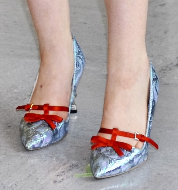 Elle Fanning’s metallic pointed-toe pumps featured shimmering silver uppers and bold red velvet T-bar straps with bow accents, adding a playful vintage touch to her look