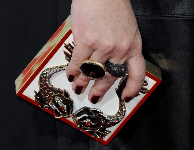 Melissa McCarthy showing off a boxy embellished clutch and stacks of rings