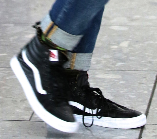 Gwen Stefani adds a cool, casual edge to her look with black leather Vans Sk8-Hi sneakers featuring the brand’s signature white side stripe, a high-top silhouette, and leopard-print sock detail peeking through