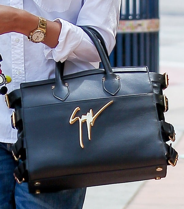 Jessica Alba carries a sleek black Giuseppe Zanotti tote, instantly recognizable by its oversized gold signature logo and edgy side buckle detailing