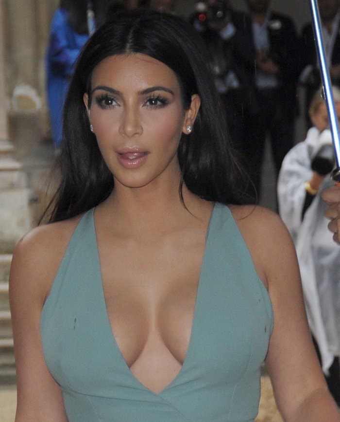 Kim Kardashian maintained her signature style by appearing in a powder turquoise, low-cut halterneck gown at the Paris Fashion Week Haute Couture Fall/Winter 2014–2015 (Valentino show) in Paris