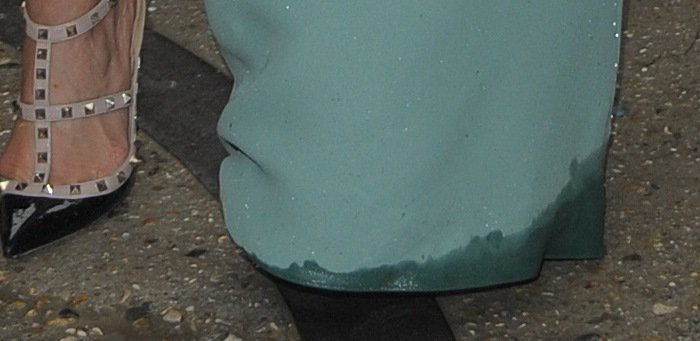 The bottom of Kim Kardashian's Valentino dress appears wet, possibly from stepping into a puddle, as she walks in her stylish Valentino Rockstud heels