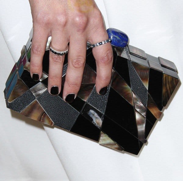 Jaimie Alexander carried a striking geometric Emm Kuo clutch, featuring metallic panels, iridescent accents, and a bold stone clasp that added edge to her minimalist ensemble