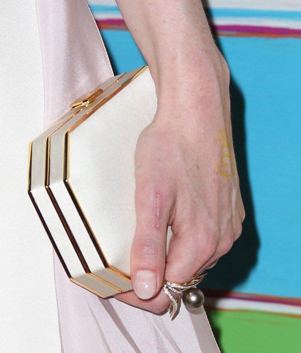Michelle Dockery accessorized with a structured white satin Amanda Pearl clutch featuring sleek gold trims and an elegant geometric shape