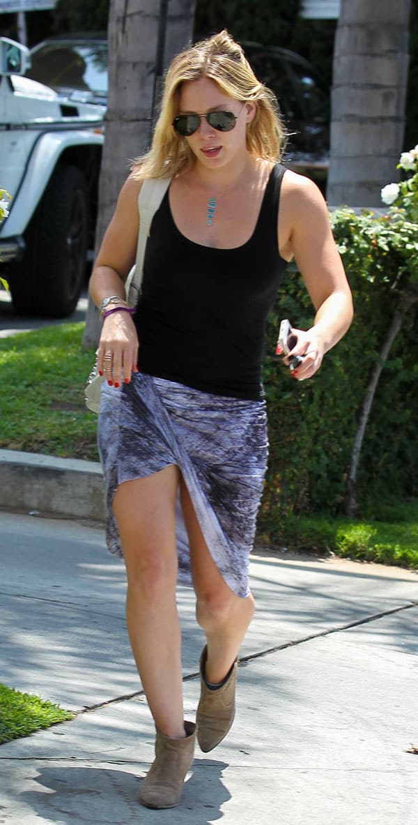 Hilary Duff in Los Angeles on August 9, 2014, wearing a Helmut Lang printed asymmetrical wrap skirt, Ray-Ban aviator sunglasses, and Laurence Dacade Pete leather ankle booties
