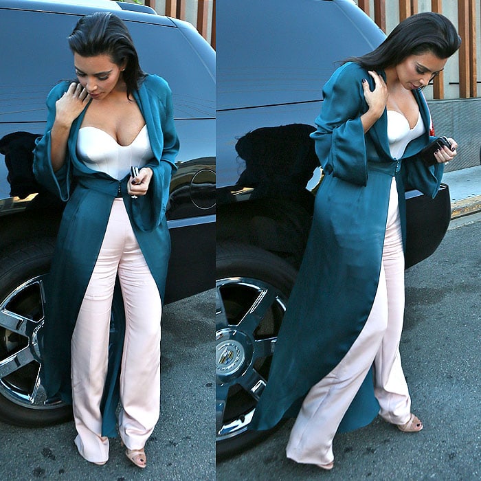 Kim Kardashian takes a moment to check herself and ensure that her outfit is perfectly in place